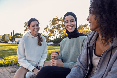 Shot of pretty sporty women having good time while talking after running while posing at camera in the parkの写真素材