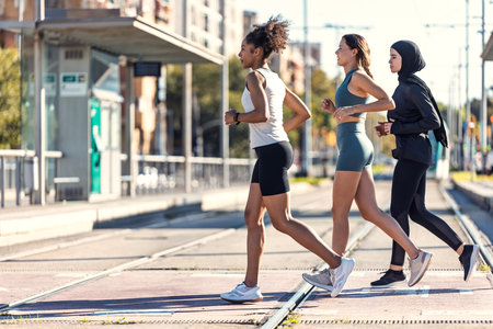 Shot of a group of three sportswomen running together through the cityの写真素材