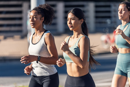 Shot of a group of three sportswomen running together through the cityの写真素材