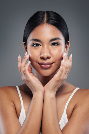 Portrait of beautiful woman posing at camera on gray isolated backgroundの写真素材