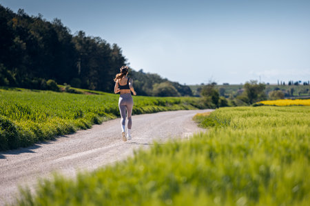 Shot of back view of sporty woman running through the countrysideの写真素材
