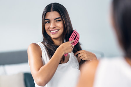 Portrait of young woman brushing her long hair in front of the mirrorの写真素材