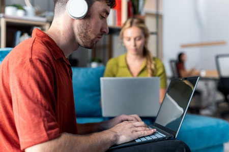 Shot of business people working with laptop while sitting on a couch in a coworking placeの写真素材