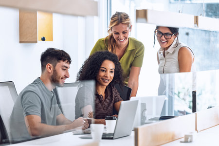 Shot of business people working with laptop and talking about their new project together in a coworking placeの写真素材