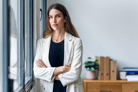 Portrait of beautiful businesswoman taking a break while looking at camera next to the window at the office.の写真素材
