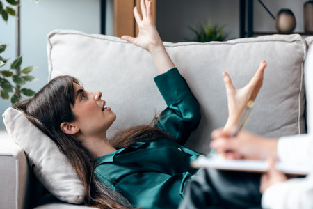 Shot of beautiful woman having therapy while the psychologist takes notes, lying on the couch in the psychology officeの写真素材