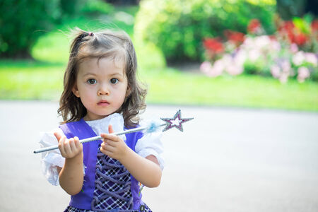 Adorable little girl with a scepter in a parkの写真素材