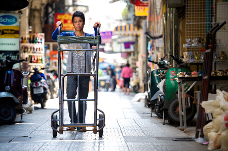 YAOWARAT, THAILAND - JANUARY 24, 2010  Unidentified thailand man pushing cart down the street get to order yaowarat market のeditorial素材