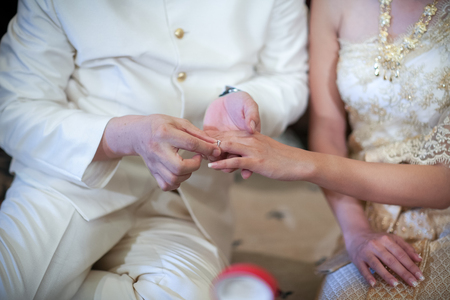 Thai groom wearing wedding ring for his brideの写真素材