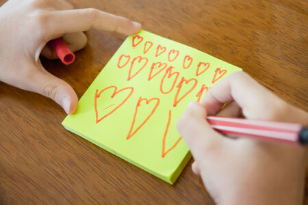 Girl hand writing a heart on the paperの写真素材