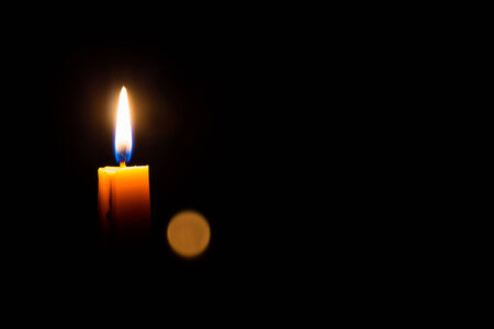 Yellow candle on the dark background and bokeh の写真素材