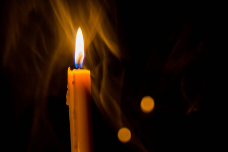 Yellow candle on the background and smokeの写真素材