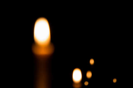 Yellow candle on the dark background and bokehの写真素材