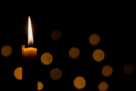Yellow candle on the dark background and bokehの写真素材