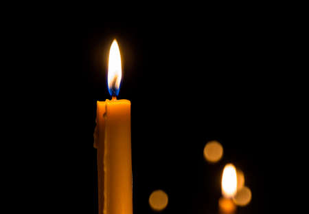 Yellow candle on the dark background and bokehの写真素材