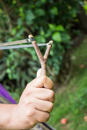 Holding slingshot in hands against green backgroundの写真素材