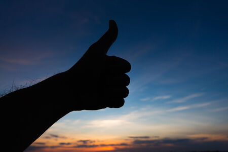 Thumbs up hand silhouette in skyの写真素材