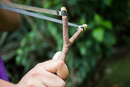 Holding slingshot in hands against green backgroundの写真素材