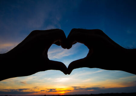 Love shape hand silhouette in skyの写真素材