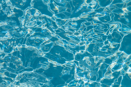 Surface of water on the swimming pool reflecting the sunの写真素材