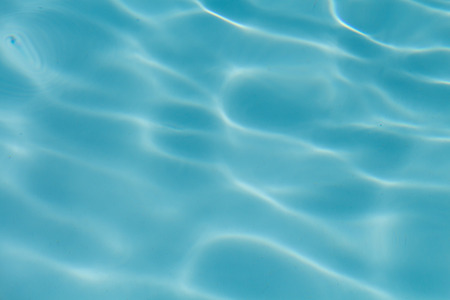 Surface of water on the swimming pool reflecting the sunの写真素材