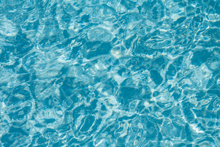 Surface of water on the swimming pool reflecting the sunの写真素材