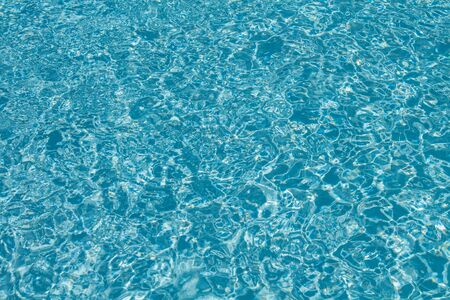 Surface of water on the swimming pool reflecting the sunの写真素材