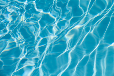 Surface of water on the swimming pool reflecting the sunの写真素材