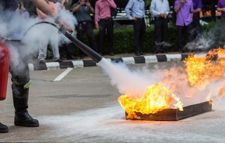 Instructor showing how to use a fire extinguisher on a training fireの写真素材