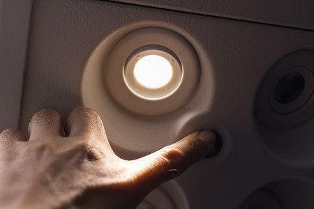 Passengers using the hand to turn off lights on the switch board on the plane.の写真素材