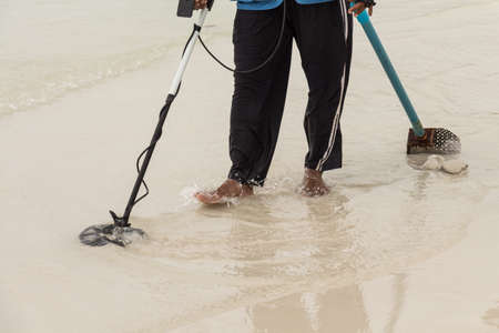 People are using special tools To find metal beneath the sand by the sea. To find the value of a lost traveler in mind.の写真素材
