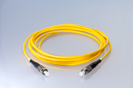 Fiber optic single mode FC jack over gray background.