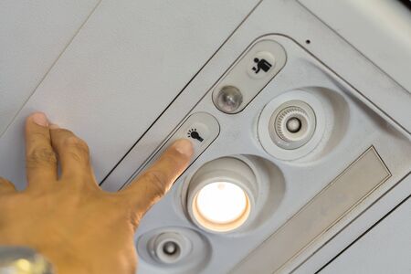 Passengers using the hand to turn off lights on the switch board on the plane.の写真素材