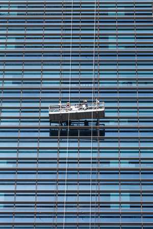 Workers cleaning windows outside service on high rise building.の写真素材