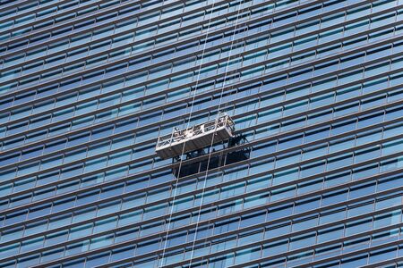 Workers cleaning windows outside service on high rise building.の写真素材