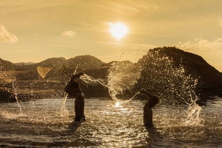 Boys playfully splashing water on each other on holiday.の写真素材