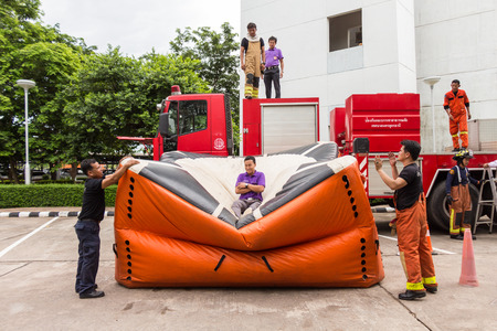 UDONTHANI, THAILAND - JULY 29, 2015:Firefighters teaching staff offices, jumping from a height into the safety air cushion in the annual fire training.のeditorial素材