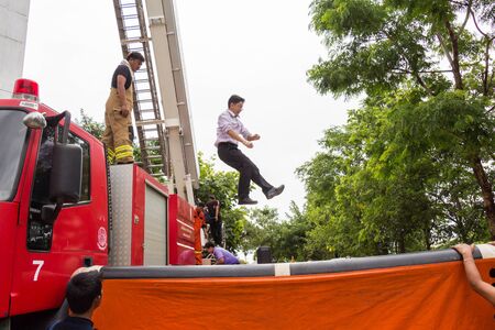 UDONTHANI, THAILAND - JULY 29, 2015:Firefighters teaching staff offices, jumping from a height into the safety air cushion in the annual fire training.のeditorial素材