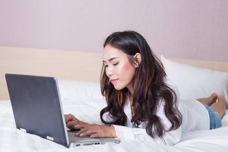 Sexy girl use computer notebook on the bed.の写真素材