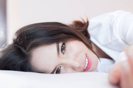 Close up of pretty girl good feeling on a bed in a bedroom.の写真素材