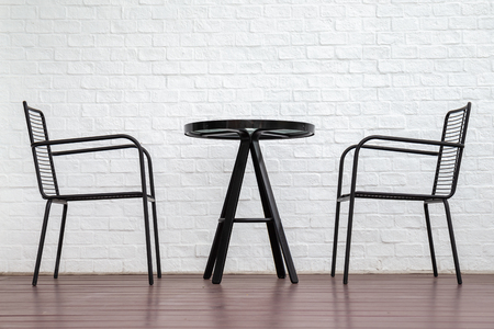 Black table and chairs on lath and white brick wall background.の写真素材