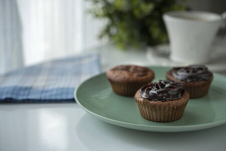 Muffin with chocolate cream next to the window with coffeeの写真素材