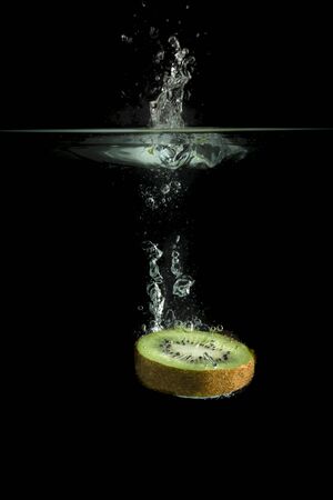 Kiwi fruit falls in waterの写真素材