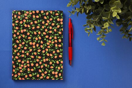 Blue texture background workspace with colorful notebook, green plant and a penの写真素材