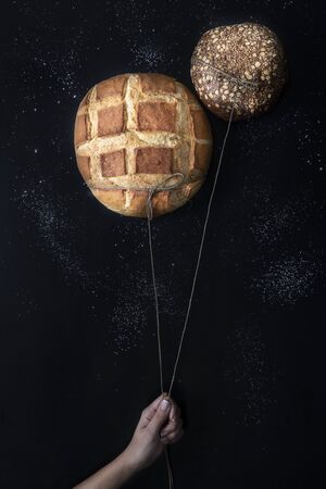 Two fresh crispy breads like balloons on a nigh sky and stars from flour in a black background