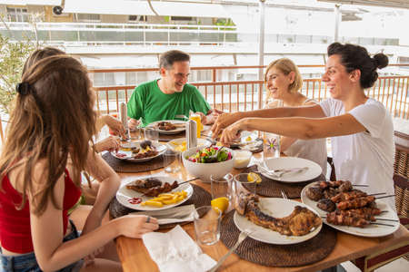 Family Dining and Having Fun Together on the Balcony. Lifestyle Concept of a Family Dinner. No filterの写真素材
