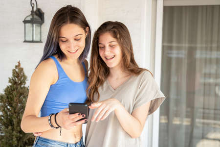 Two Sisters Laughing Having fun With a smart Phoneの写真素材