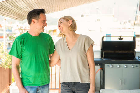 Middle age couple, man and wife, talking and laughing at the balcony. Man and wife good relationship conceptの写真素材
