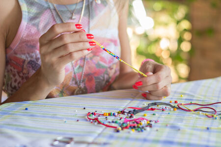Woman making bracelet of colorful beands with her handsの写真素材