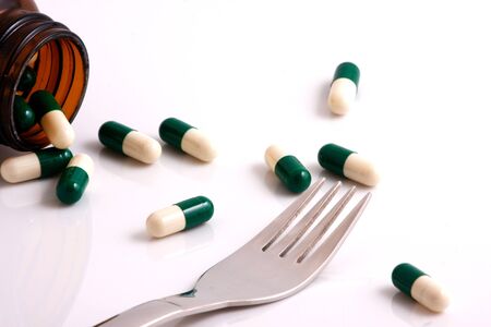 Medicine capsules and pills with fork and knifeの写真素材